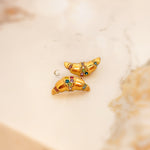 Pair of gold croissant-shaped earrings with multicolored cubic zirconia on a light background