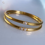 Two gold rings with two zircon stones each, close-up on white background