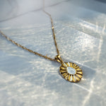 Delicate white enamel flower necklace from Avyrona Earth Collection, displayed on a porcelain plate with soft grooves, captured in natural light.