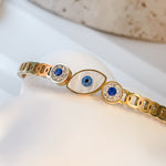 Elina bangle bracelet with protective Evil Eye detail and side clasp, displayed on white marble