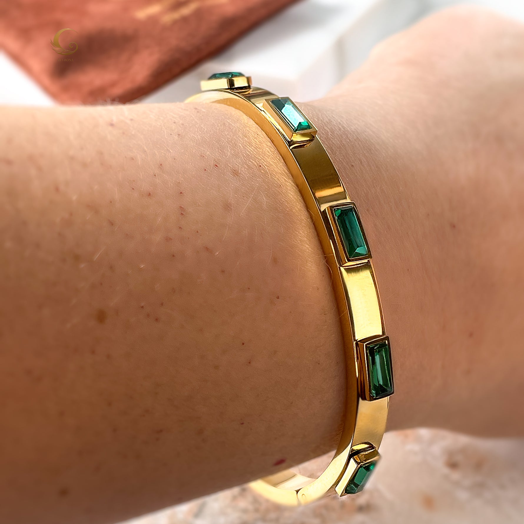 Model wearing the gold-plated emerald crystal bangle bracelet on wrist, showcasing fit and shine in natural light.
