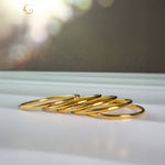 Five minimalist gold zircon rings laid side by side on a white surface
