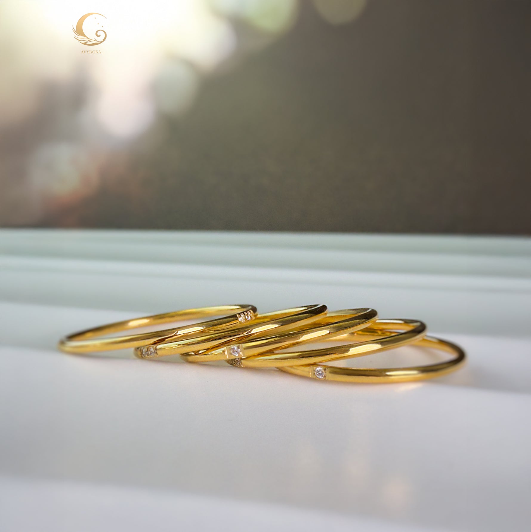 Five minimalist gold zircon rings laid side by side on a white surface