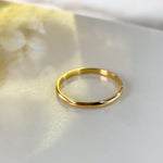 Minimalist gold 2mm band photographed individually with soft golden tones.