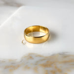 6mm gold ring band laid flat on white and gold marble.