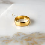 Thick 6mm gold ring band shown flat on soft beige surface.