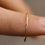Thin gold zircon ring shown on finger, close-up macro shot