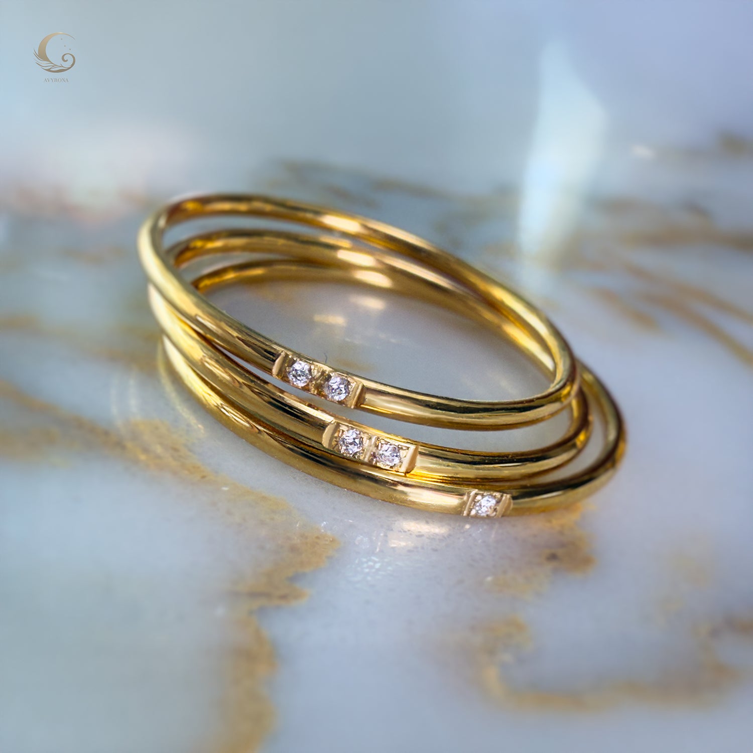 Three gold rings with zircon stones, laid on marble surface