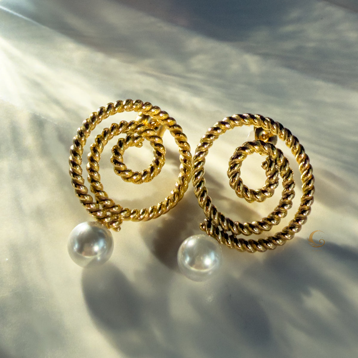  Thaleia gold earrings glowing in warm sunlight with pearl-like accents