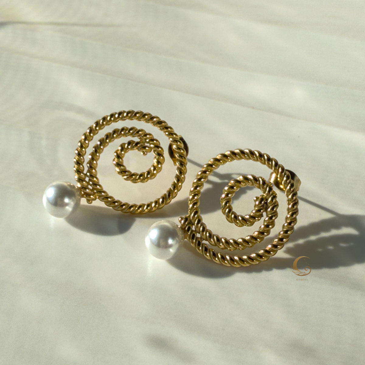 Thaleia earrings in gold with luminous pearl-like details on clean white backdrop