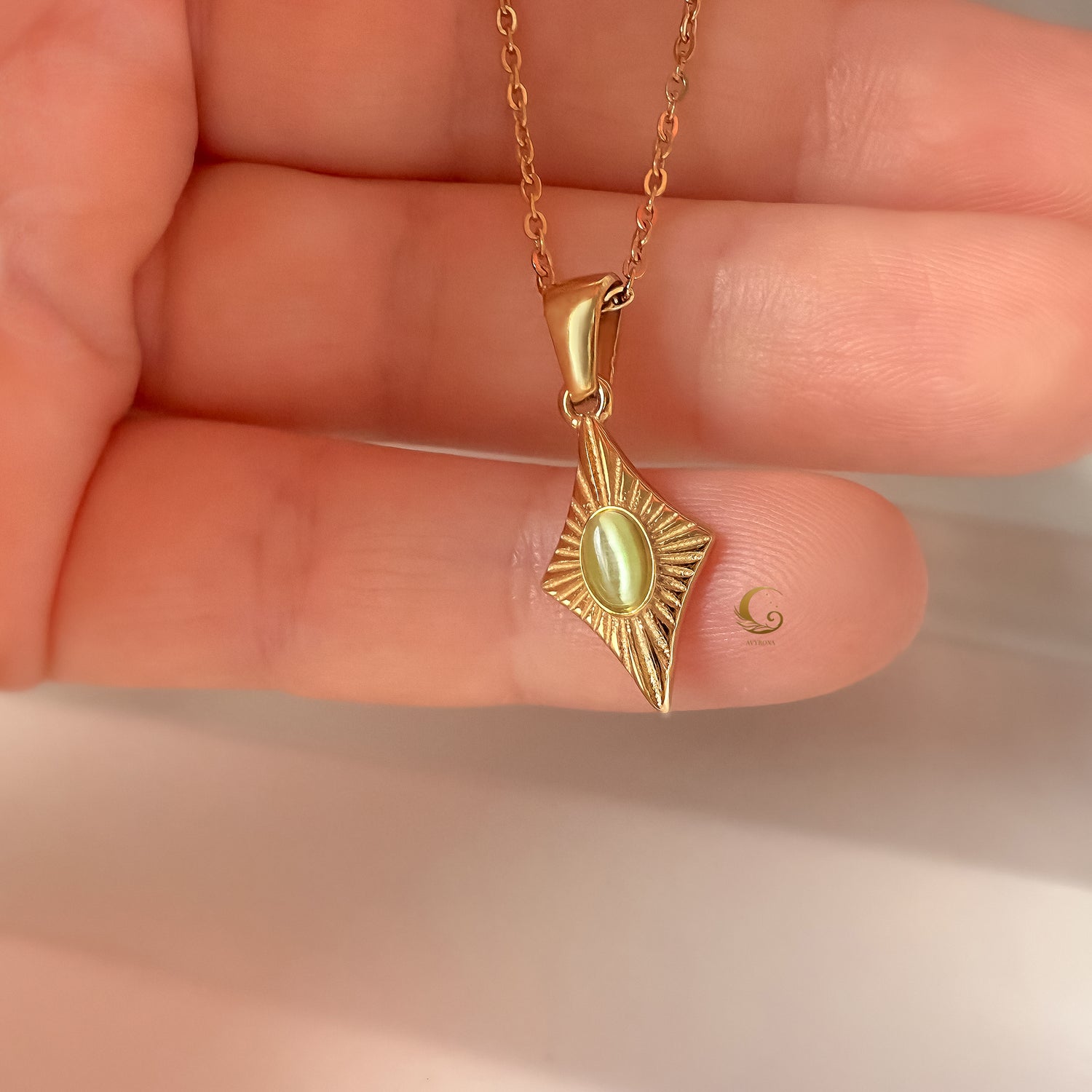 Guardian Amulet necklace with green cat eye pendant shown resting on fingers for scale and detail.