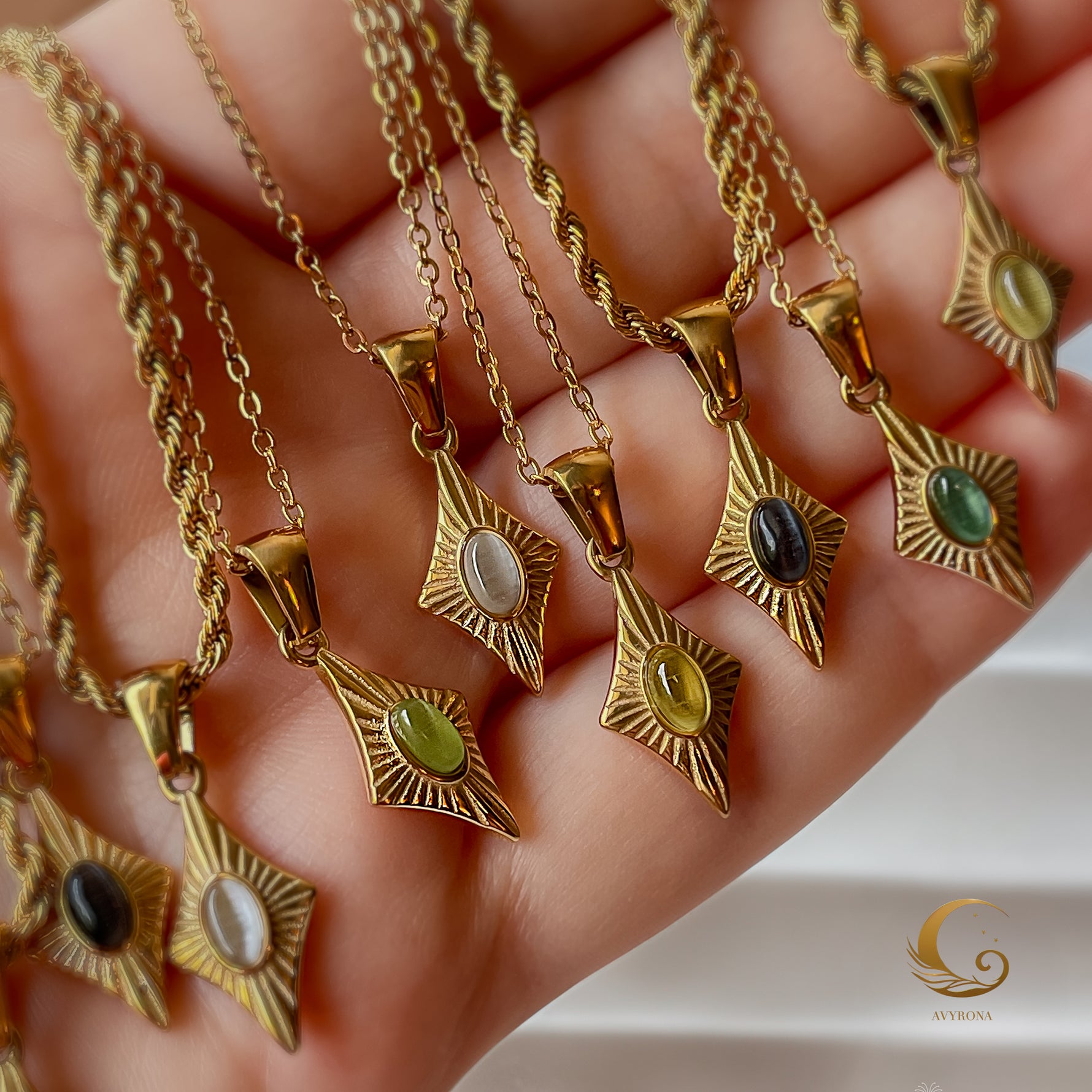 Set of Guardian Eye necklaces in various stone colors including blue cat eye, black, white, green, and yellow, shown in a hand.