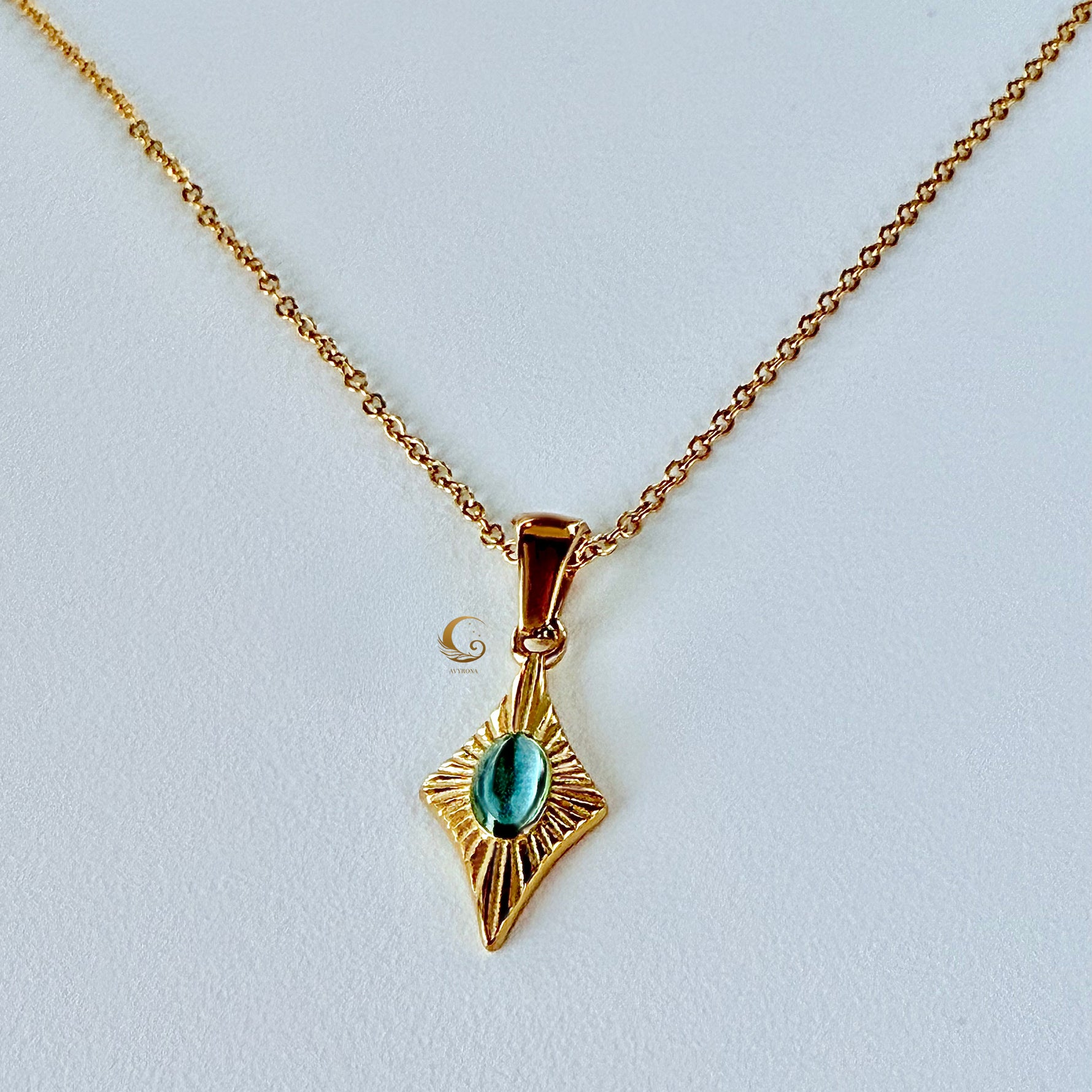 Guardian Eye necklace featuring a blue cat eye stone on a twisted gold rope chain, photographed on a light plain background.