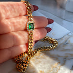 Harper Bracelet with emerald green crystal held in hand, showcasing thick cuban chain links and sparkling details.
