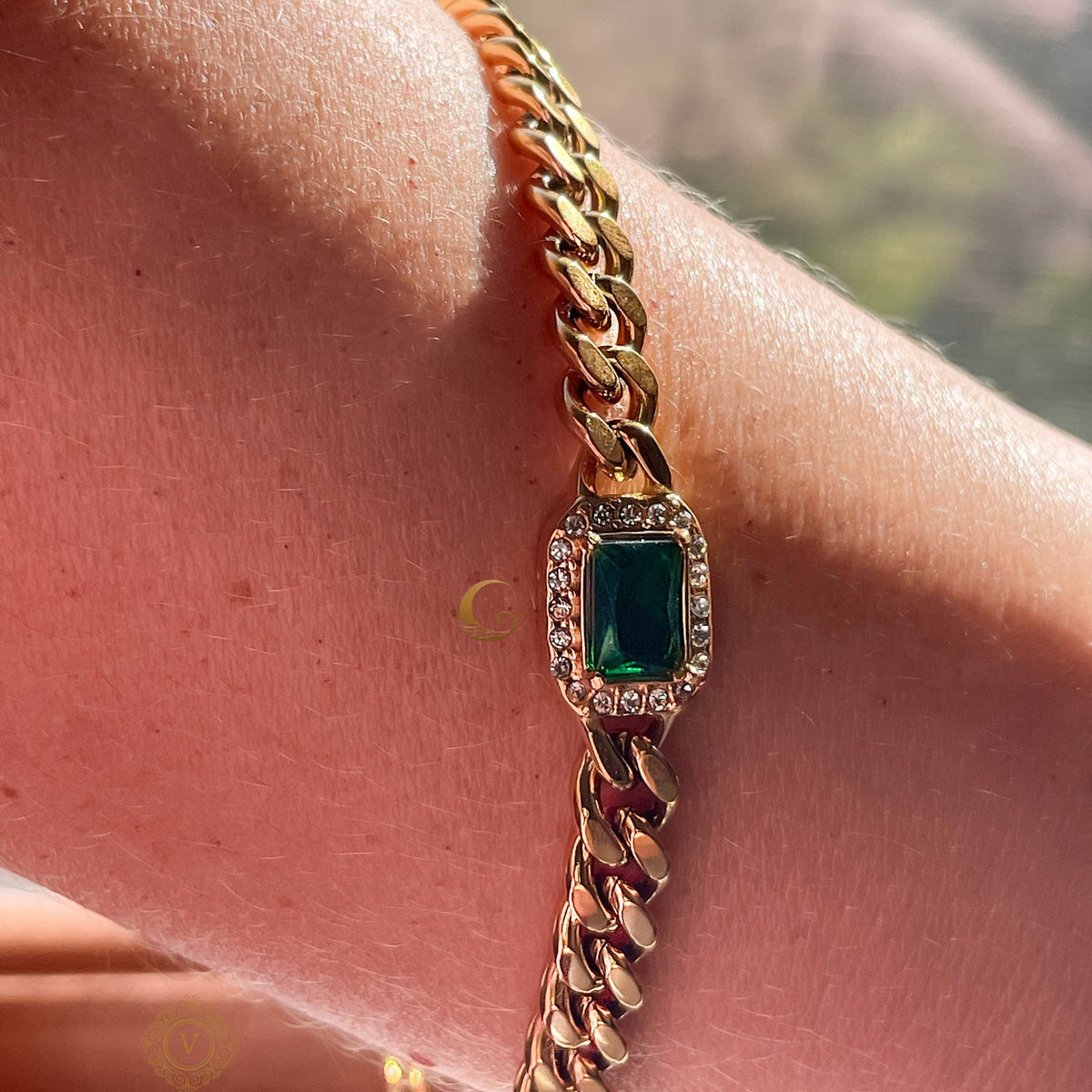 Harper Bracelet worn on wrist in natural light, showing green crystal and gold chain against skin.
