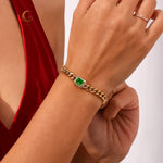 Harper Bracelet worn on wrist with red dress, showcasing gold cuban chain and vivid green crystal in natural light.