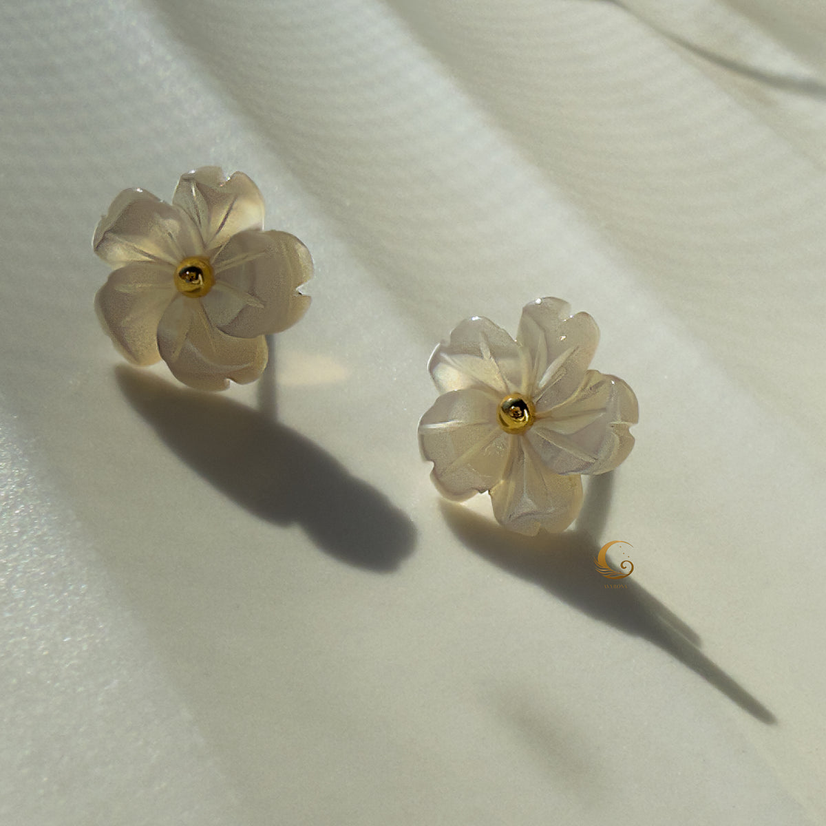  Imira natural shell flower earrings on soft fabric with warm lighting and delicate shadows