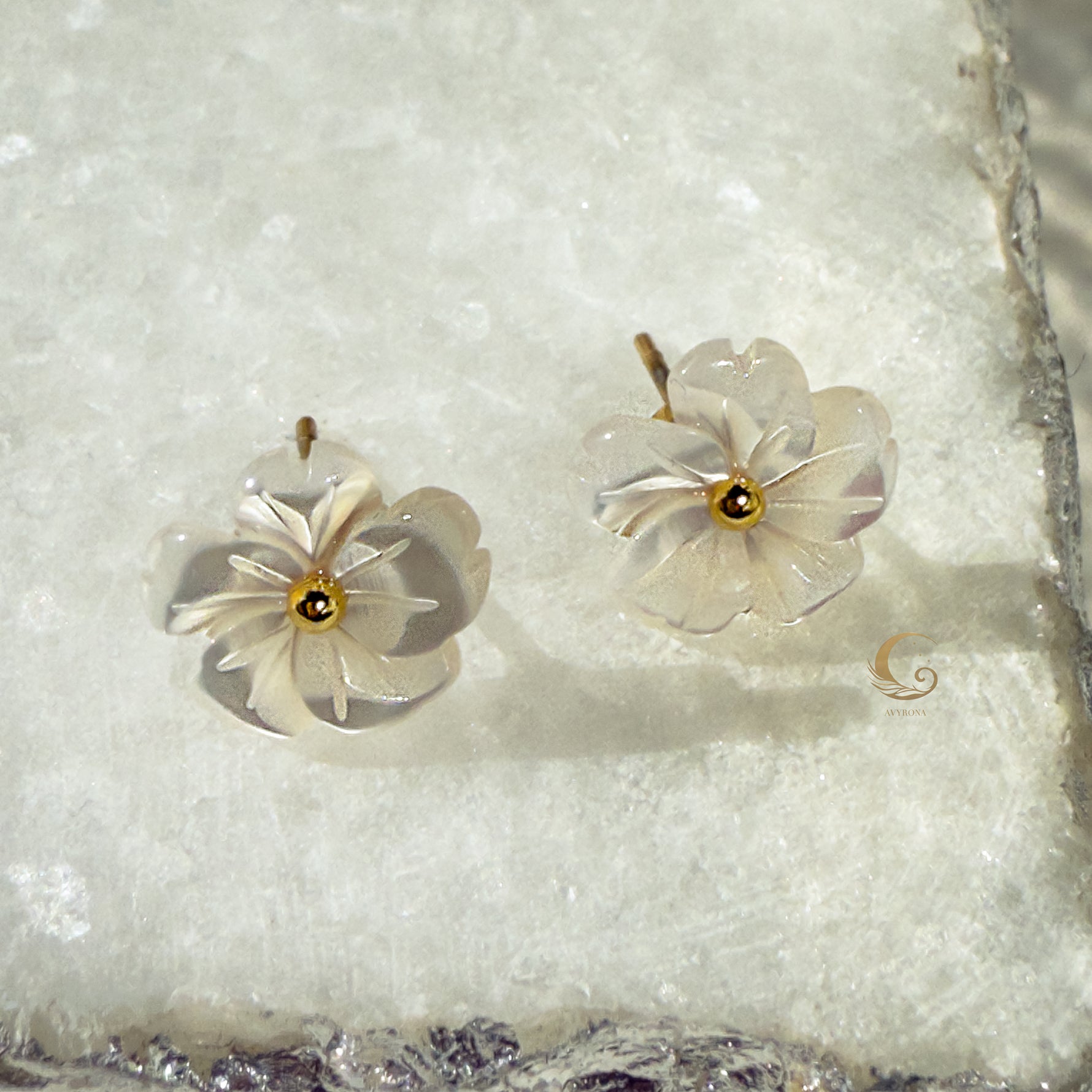 Imira flower earrings photographed on textured marble, highlighting layered petals and gold detail