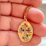  Close-up of the Isadora pendant held in hand, highlighting the vibrant gemstone cross design.