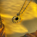 Close-up of black flower pendant on twisted gold chain, highlighting vintage-inspired floral detailing.