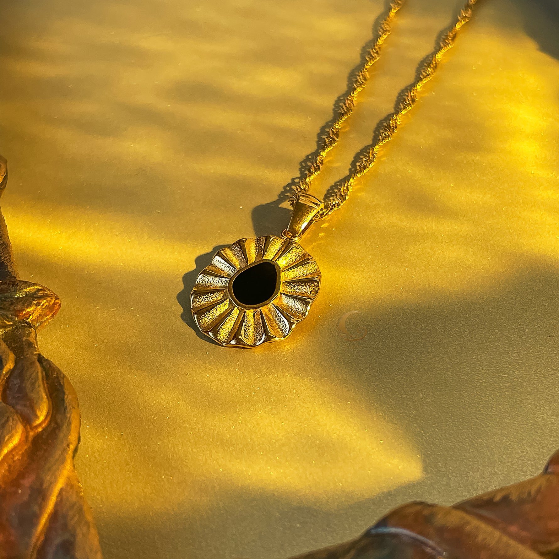 Close-up of black flower pendant on twisted gold chain, highlighting vintage-inspired floral detailing.