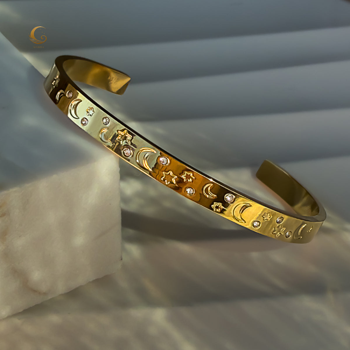 Angled shot of gold celestial cuff bracelet reflecting soft light, with clear view of its moon and star engravings.