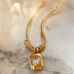 Pendant close-up showing sparkle of heart zirconia, laid on velvety textured surface.