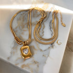 Margaret necklace styled with chain extension visible, shown on marbled surface.