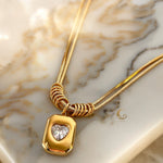 Margaret necklace displayed diagonally on marble with soft shadow and full pendant details visible.