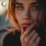 Close-up of a woman’s face wearing a stack of thin gold zircon rings on her finger