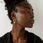 Woman wearing Thaleia spiral earrings in gold with pearl-like drops, inspired by ocean waves