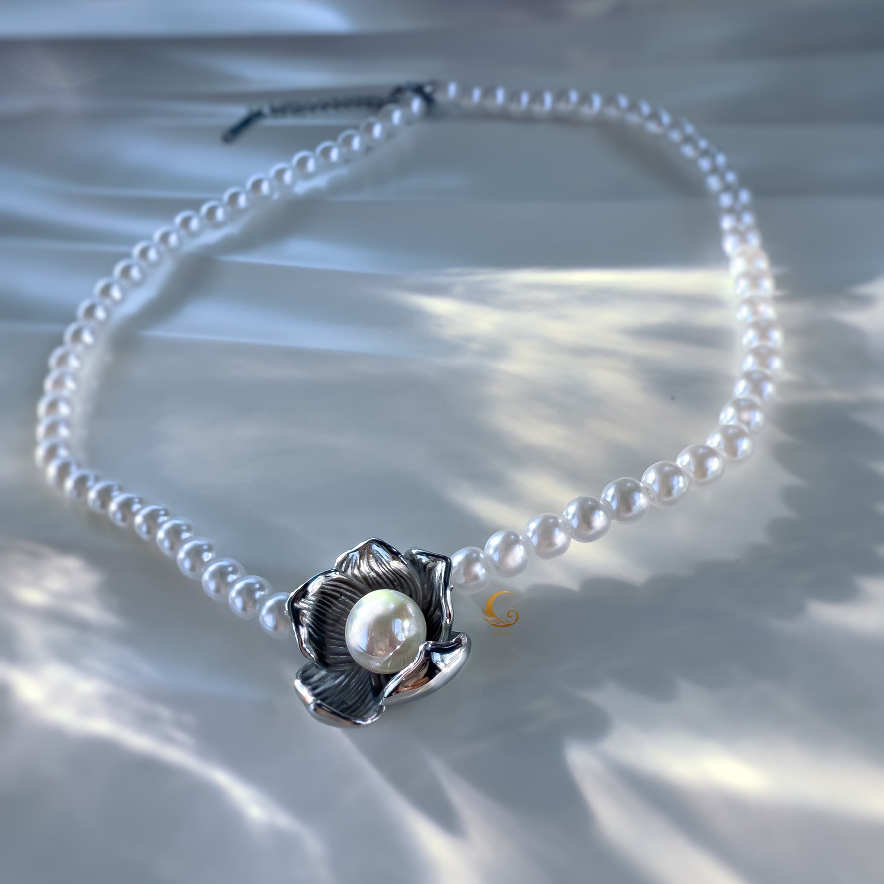Silver flower pearl necklace displayed flat on satin background