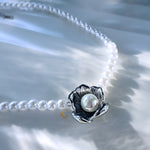 Close-up of silver floral pendant with pearl centerpiece