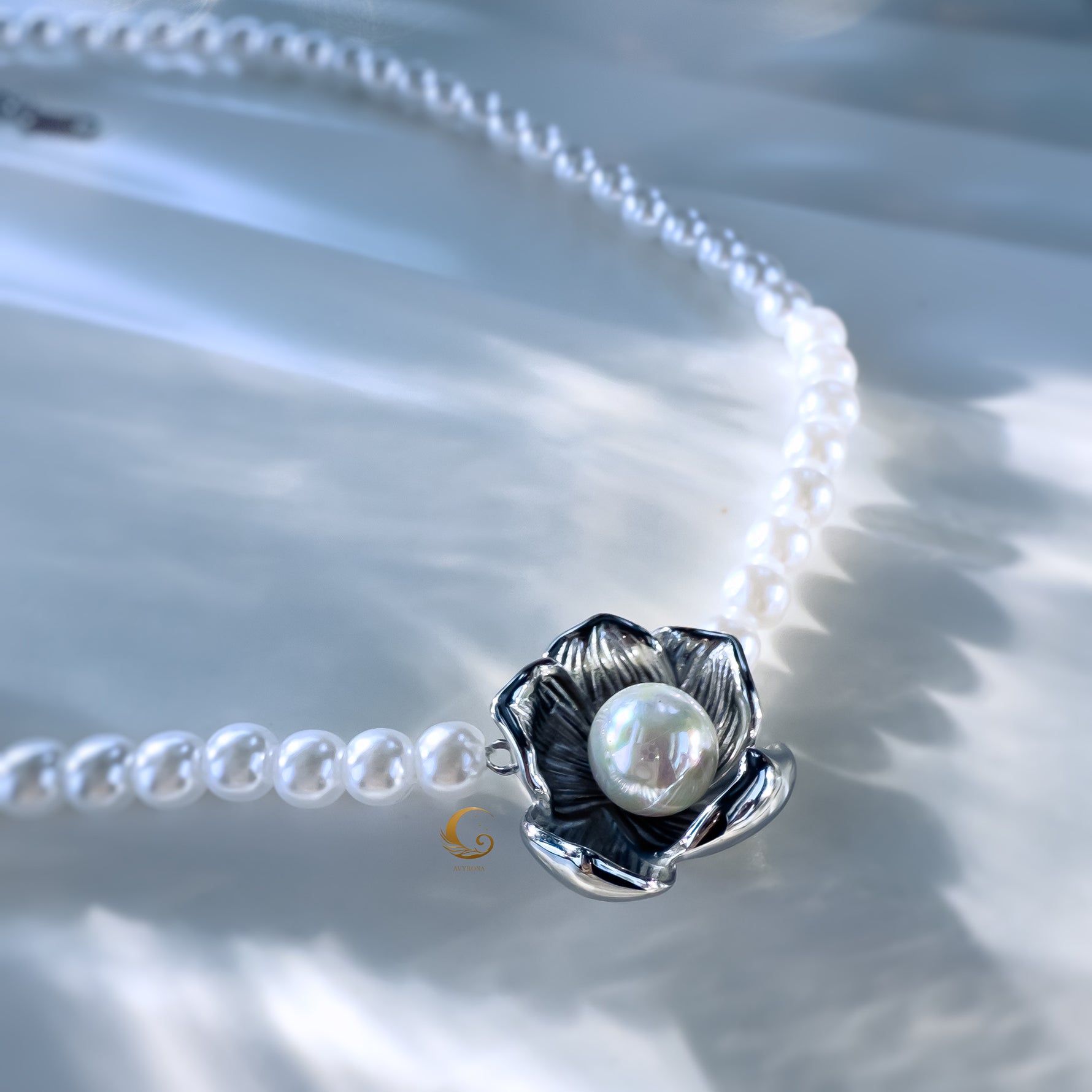 Close-up of silver floral pendant with pearl centerpiece