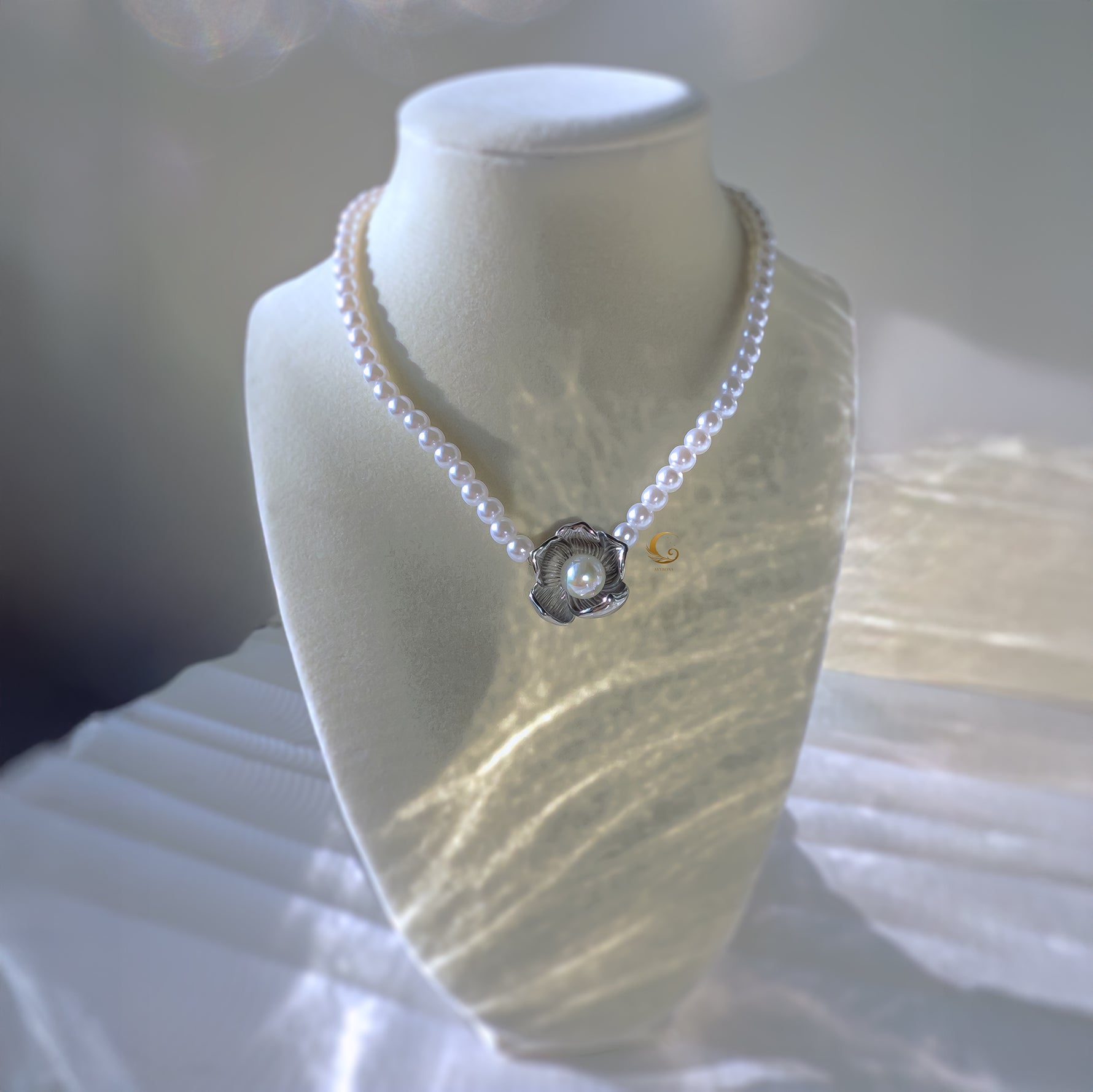 Silver flower pearl necklace on display bust with glowing backdrop