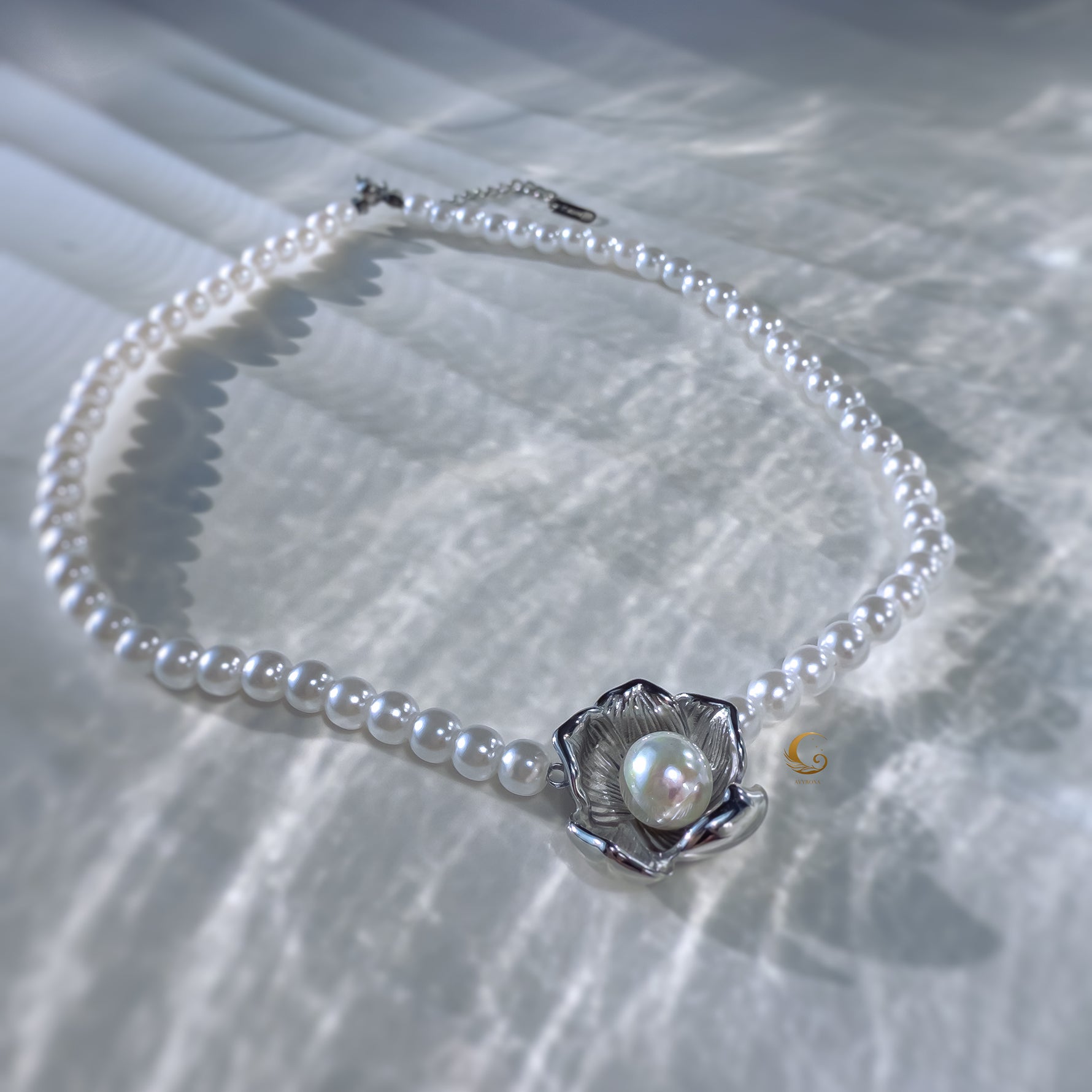 Top view of silver flower pearl necklace on reflective surface