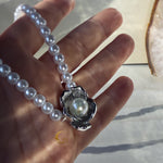 Silver flower pearl necklace held in hand showing details