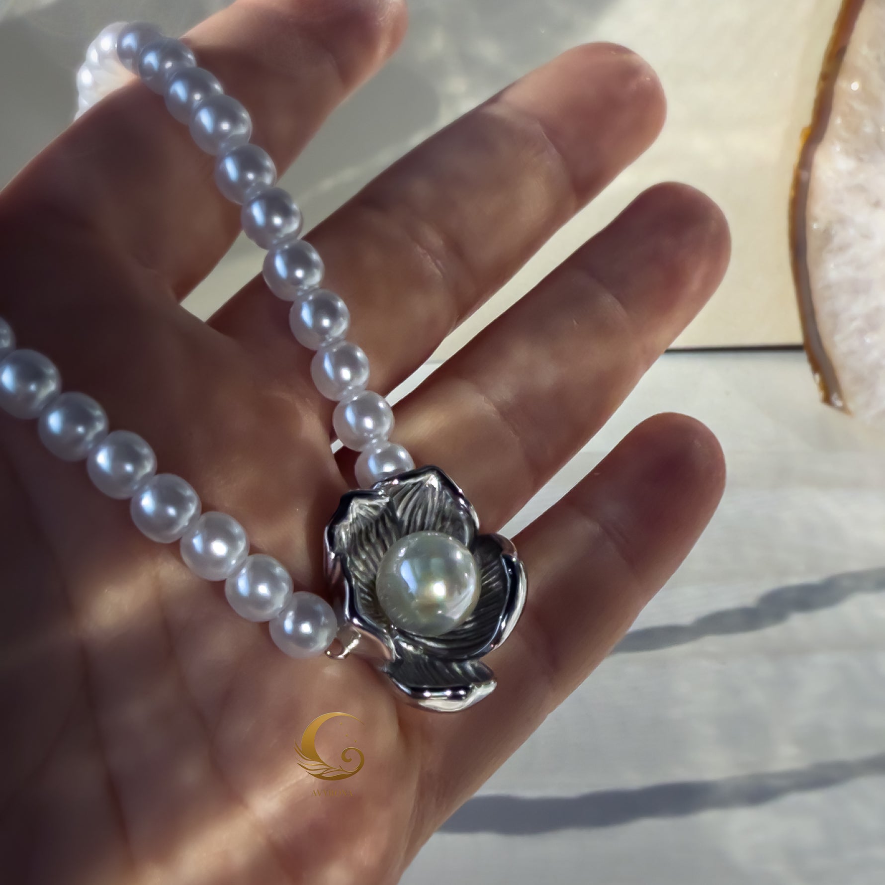 Silver flower pearl necklace held in hand showing details