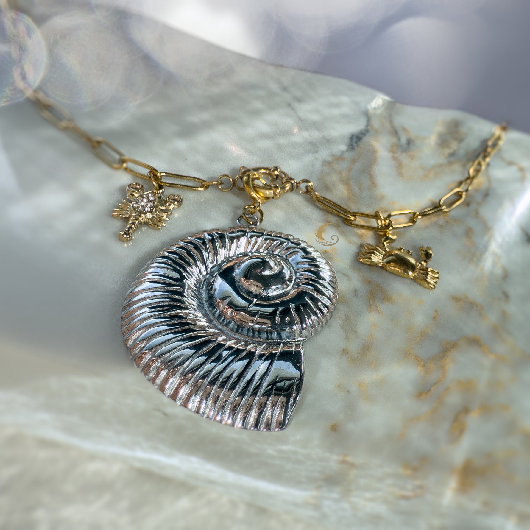Nerida necklace showing toggle clasp, silver shell, gold crab and lobster on marble