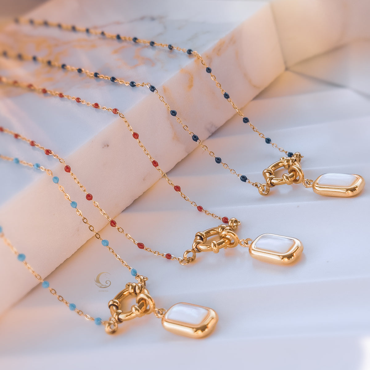 Multiple color variants of the Nerina necklace arranged in rows, showing red, blue, and light blue beads with pearl pendants