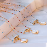 Multiple color variants of the Nerina necklace arranged in rows, showing red, blue, and light blue beads with pearl pendants