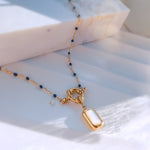 Nerina necklace laid flat on soft white fabric, showcasing the toggle clasp and deep blue beaded chain