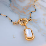 Close view of the gold toggle clasp and mother of pearl pendant from the Nerina necklace, with navy beaded chain