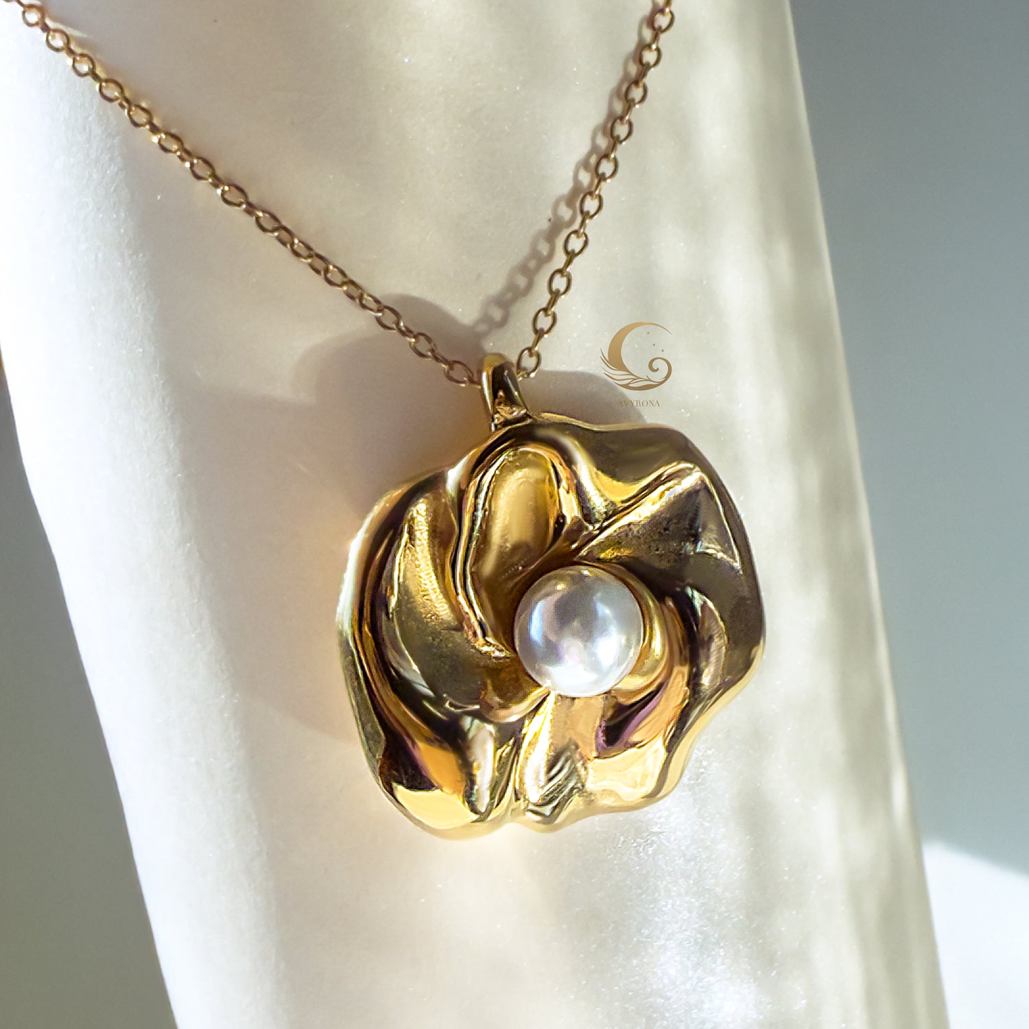 Front view of Nymira necklace pendant, gold flower design with central pearl