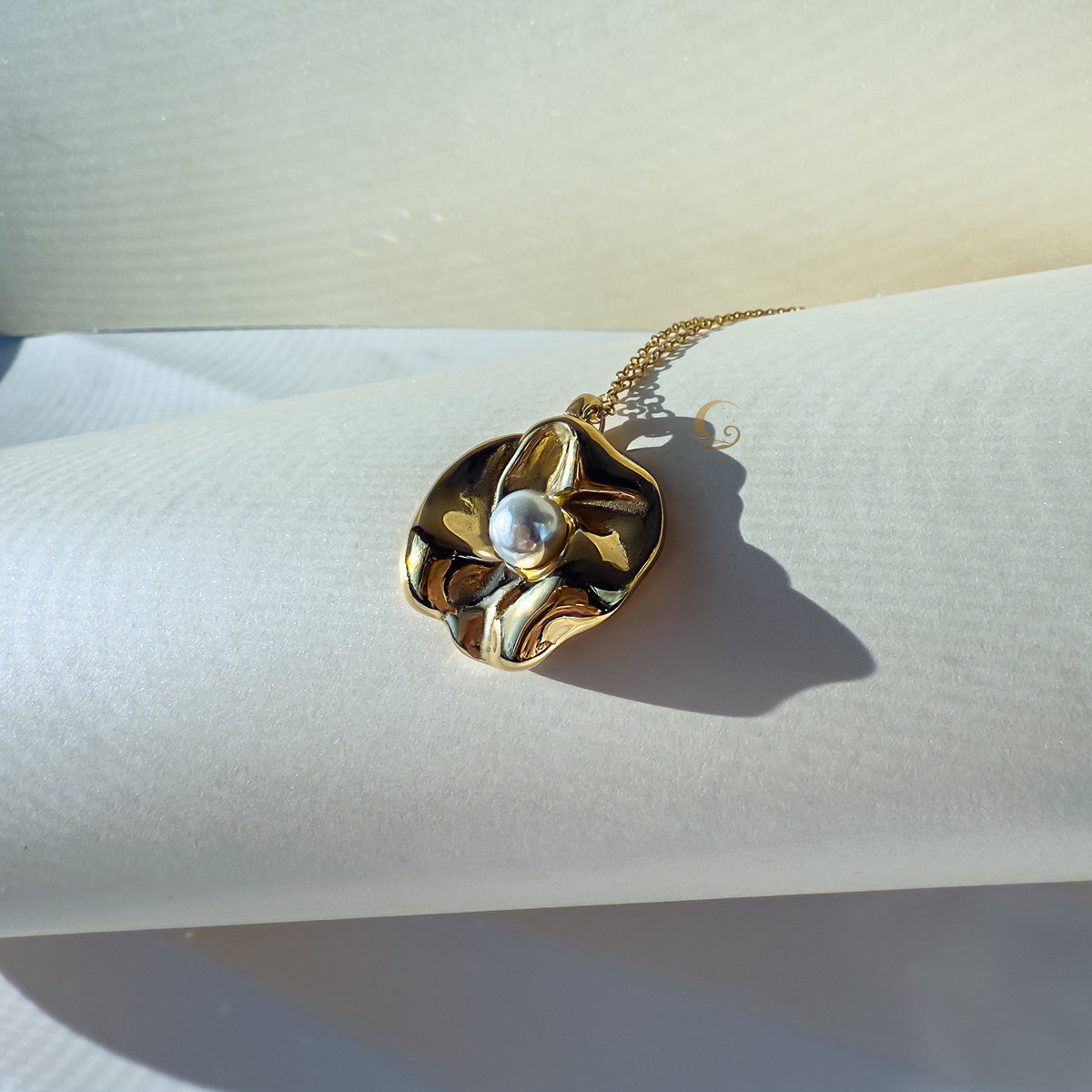 Golden Nymira pendant with pearl glowing in warm afternoon sunlight