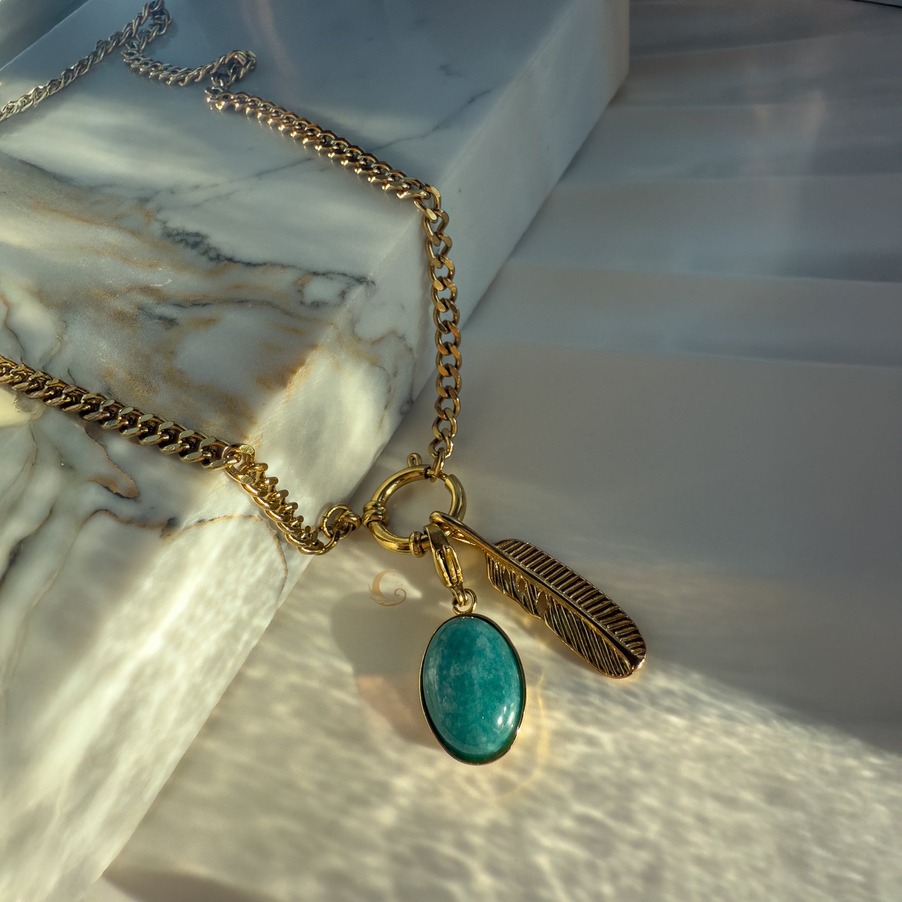 Close-up of turquoise stone and feather charm on marble background