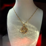 Celestial moon and planet necklace on bust display, gold paperclip chain reflecting warm light.