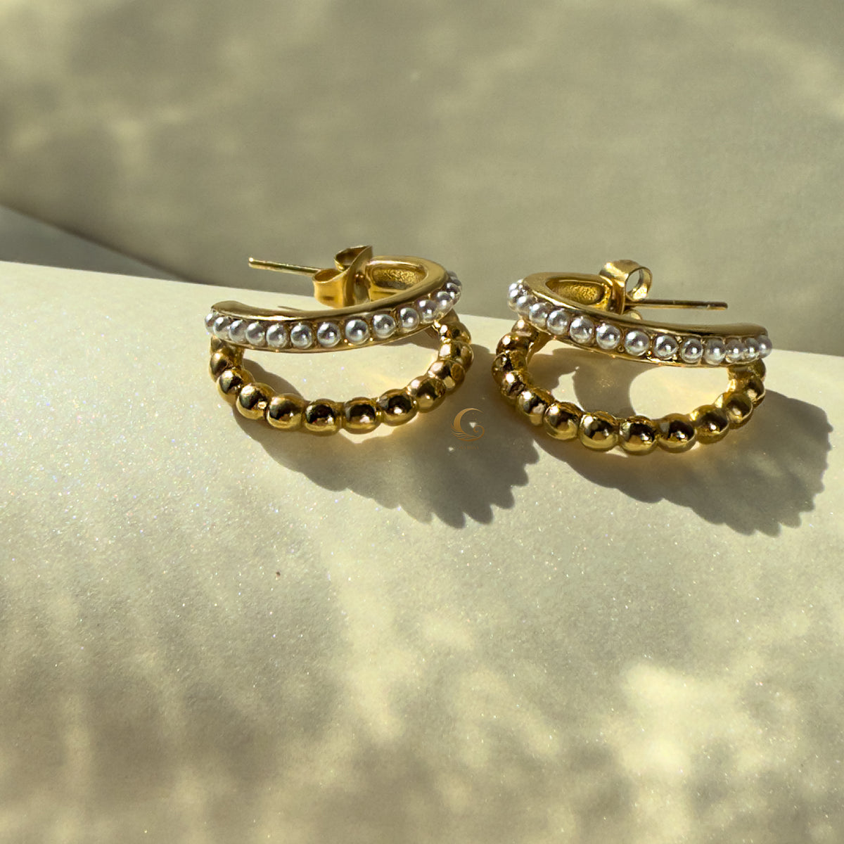 Artistic flatlay of Serina earrings with visible shadow play on matte white surface