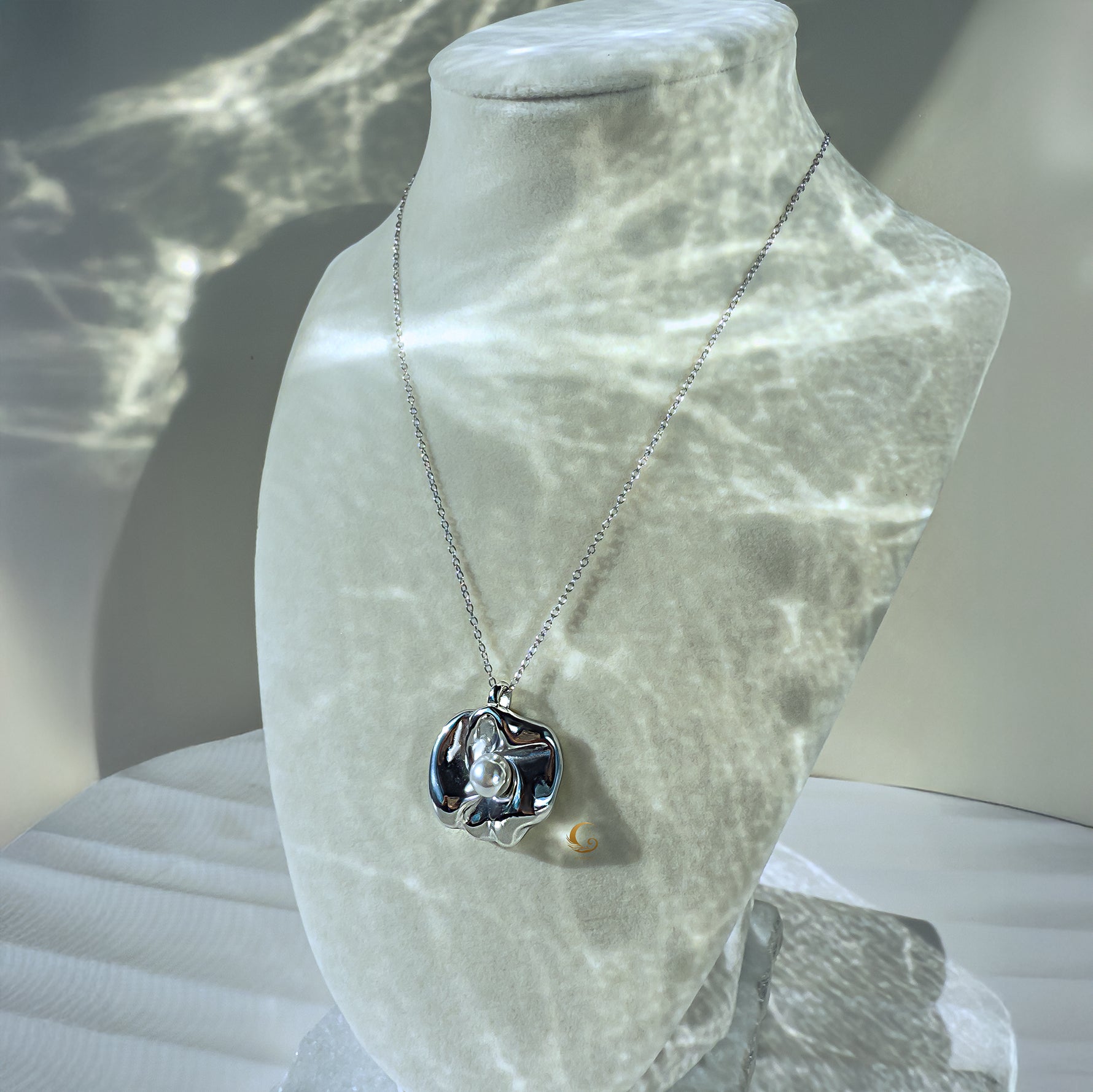 Silver flower necklace with pearl displayed on a jewelry bust with light reflections