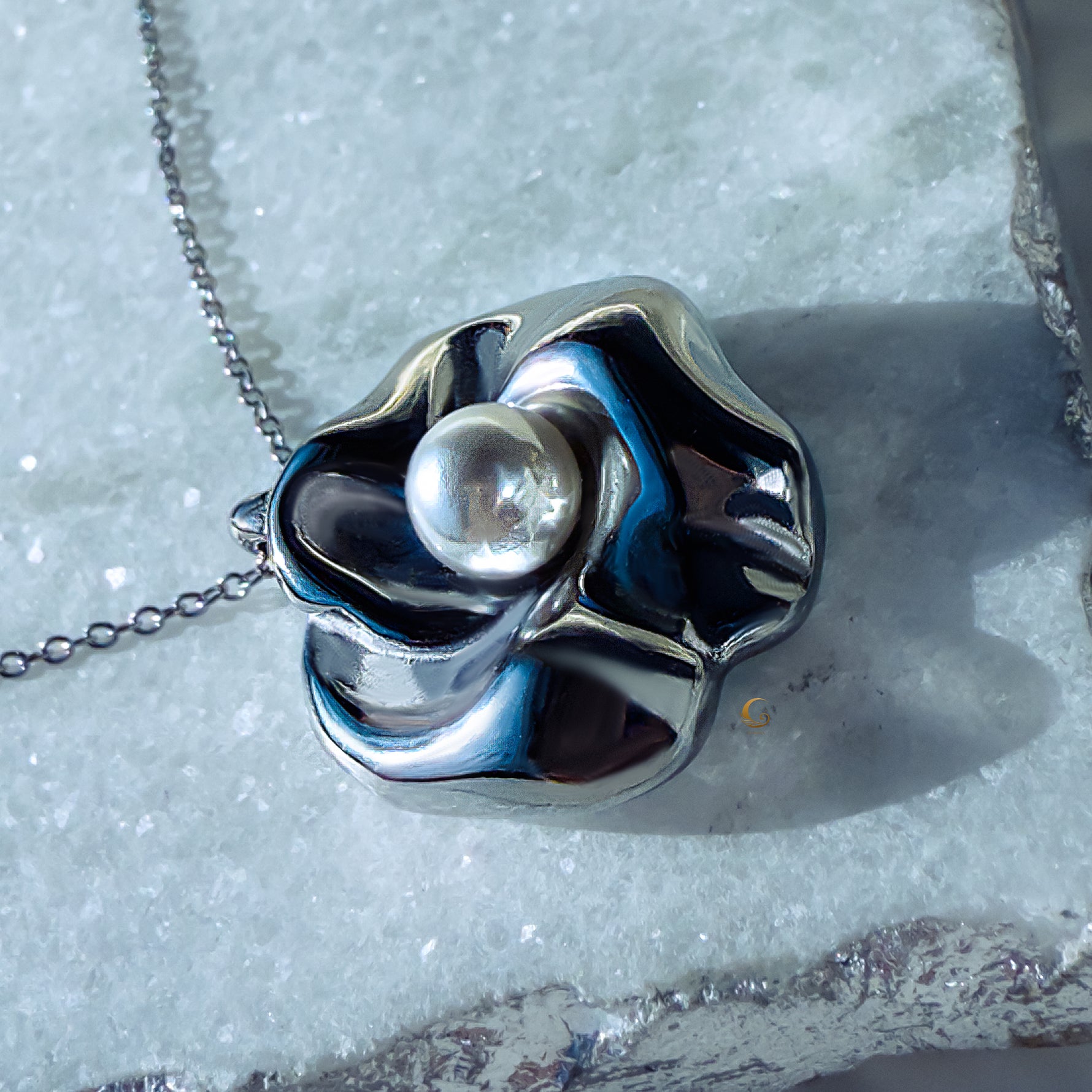 Sculpted silver flower pendant with pearl placed on light natural stone